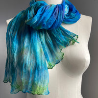 It has been created with Shibori dyeing technique on 100% pure silk crinkle chiffon and is totally unique. A piece of art to wear!  The silk chiffon is Summer weight (5 mm) and light and diaphanous with a crinkle texture that gives it body, interest, and charm. The finely finished hand-rolled piece measures flat at 22” X 72” but looks narrower with its crinkles.  Mix of vibrant blue, pale teal, fresh greens and a bit of purple