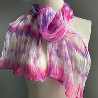It has been created with Shibori dyeing technique on 100% pure silk crinkle chiffon and is totally unique. A piece of art to wear!  The silk chiffon is Summer weight (5 mm) and light and diaphanous with a crinkle texture that gives it body, interest, and charm. The finely finished hand-rolled piece measures flat at 22” X 72” but looks narrower with its crinkles.  Mis of hot pink, purple on white background