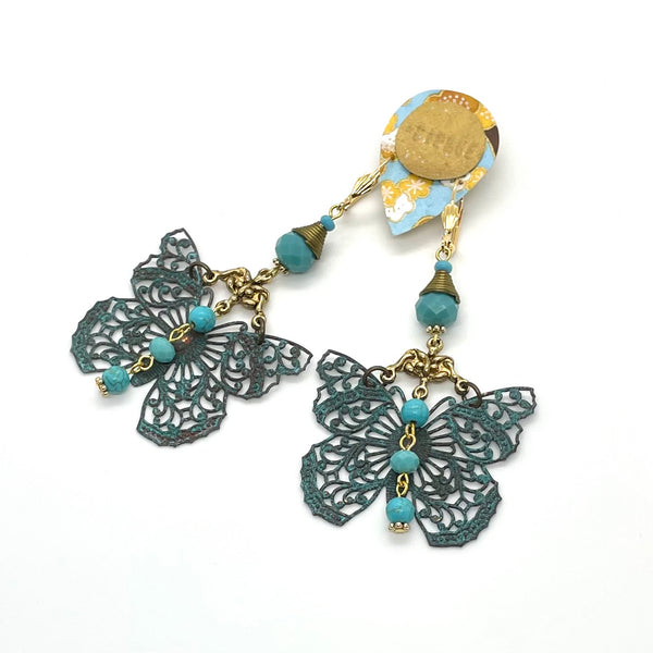 The gemstone theme is named "Patience” and it is part of a collection created to nurture and foster the feeling of patience and calm in our life. These earrings are fashioned of tinted howlite beads in a gorgeous turquoise shade, faceted crystal beads, bronze decorative element and findings and present beautifully detailed patina copper butterfly charm. They are finished off with gold-plated lever-backed hooks and and tiny flower beads. They measure approximately 3 1/4" in length and weigh 16g/pair.