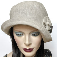 Find this handmade “Cloche” hat by local artisan Sue Scott at Eclection Ottawa. It is fashioned in mid-weight 100% linen in a soft neutral sand shade that will become your go to summer hat for years to come. The shape is a classic rounded cloche crown with a flexible brim that can be styled easily. This hat is finished with hand-sewn double cockade rosette trim in the same fabric adorned with a vintage button at its center. It is fully lined with satin and is a size-medium at approx 22 ½.’’ 